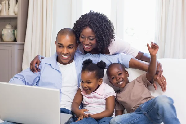 Happy family on the couch together using laptop