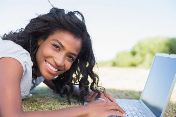 Woman lying on the grass using her laptop