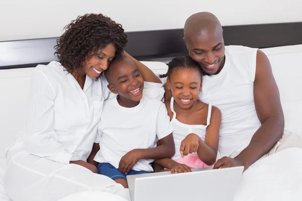 Happy family using laptop together in bed