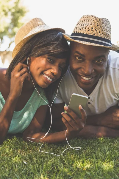 Happy couple lying in garden together listening to music