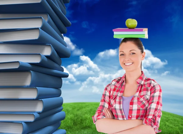 Student holding an apple and books on head