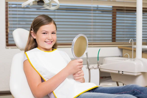 Girl holding mirror in dentists chair