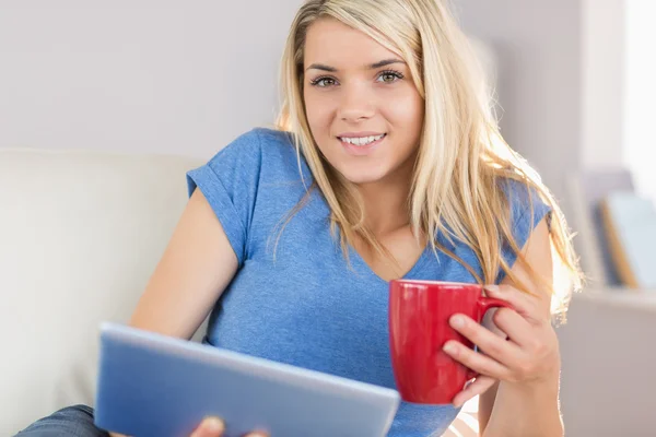 Beautiful woman using digital tablet while drinking coffee
