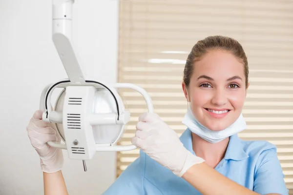 Dental assistant smiling at camera beside light