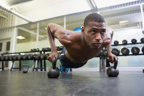 Man doing push ups with kettle bells