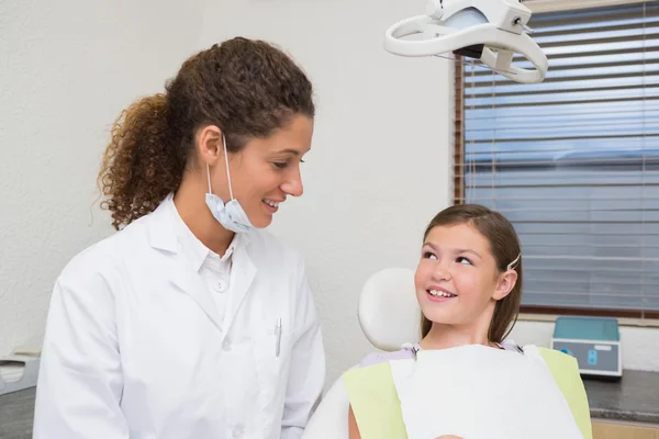 Pediatric dentist smiling with little girl in the chair