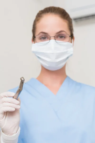 Dentist in blue scrubs holding drill