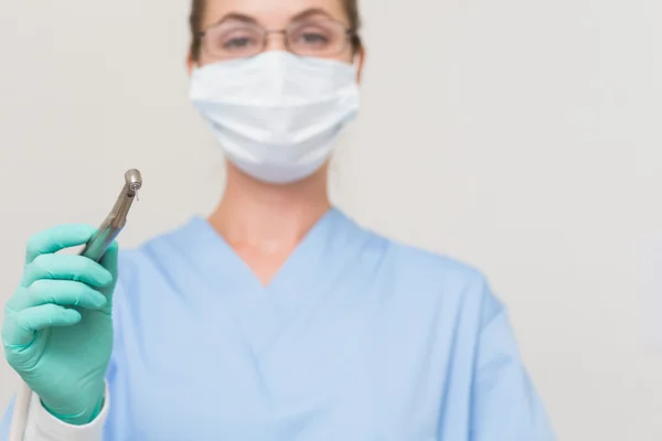 Dentist in blue scrubs holding drill