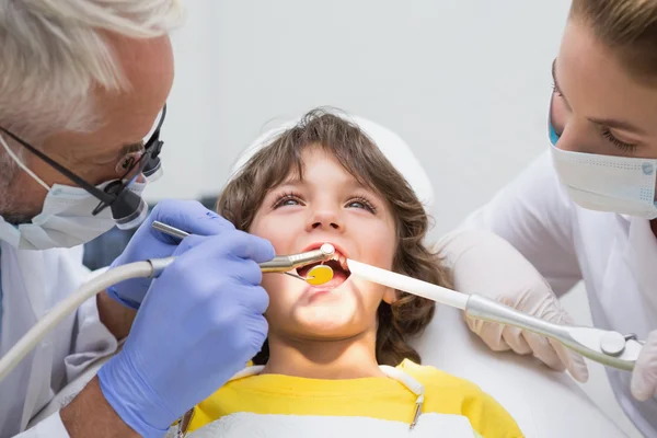 Dentist and assistant examining boys teeth