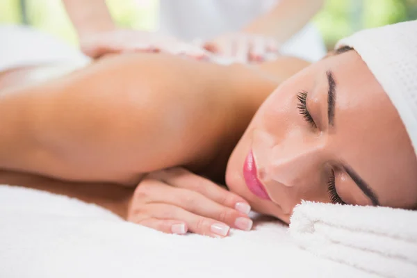 Attractive woman receiving back mask cream at spa center