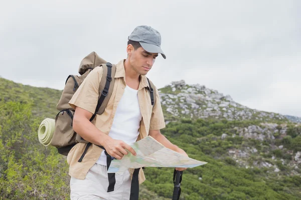 Hiking man holding map on mountain terrain