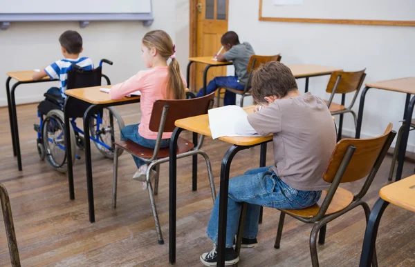 Disabled pupil writing in classroom