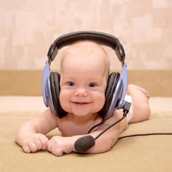 Newborn baby boy with blue eyes smiling wearing a headset.
