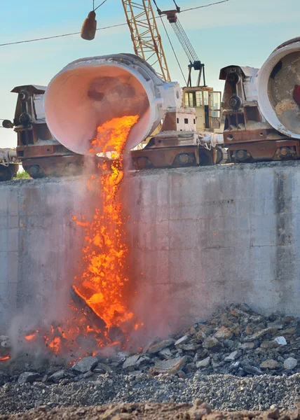 The molten slag is poured from a cup on a railway platform