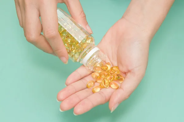 Woman \'s hand take vitamin Omega-3 fish oil pills