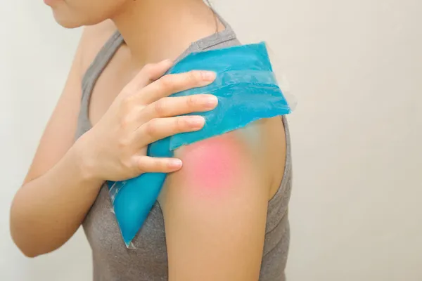 Woman applying cold pack on swollen hurting shoulder