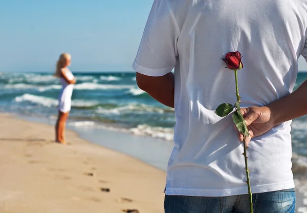 Loving couple, man with rose waiting his woman on the sea beach