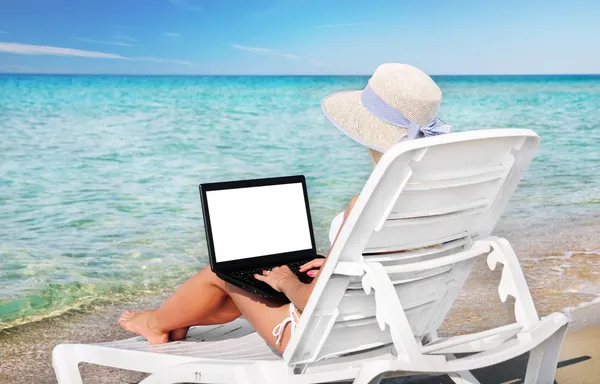 Cute woman with laptop in lounge on summer beach