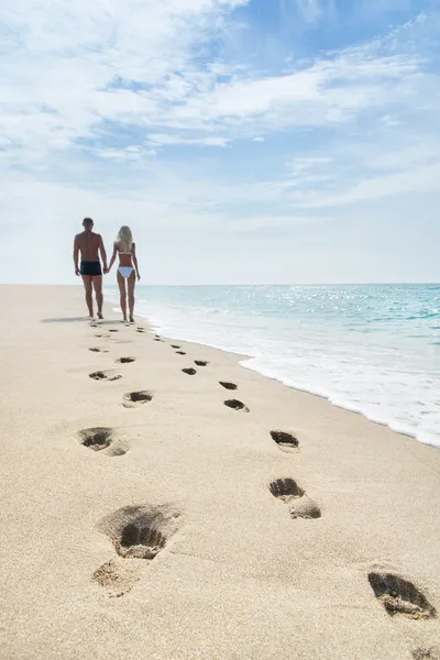 Loving couple walking with footprints at sea sandy beach