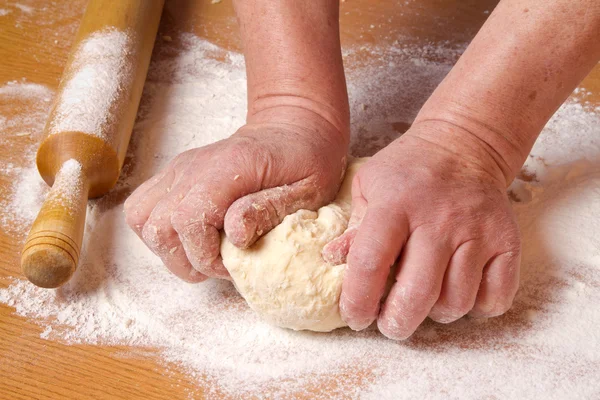 Hands of the baker knead a piece dough
