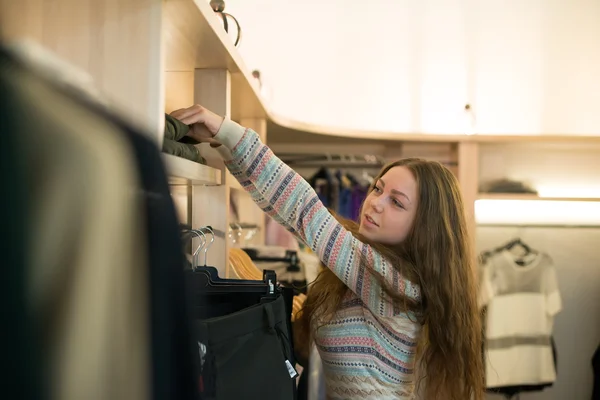 Woman shopping choosing dresses looking in mirror uncertain