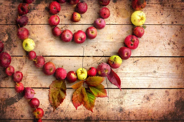 Vintage Autumn border from apples and fallen leaves on old wooden table.