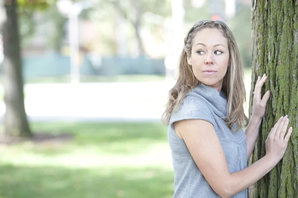 Woman outdoors posing near a tree