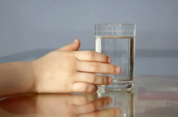 Hand of child and glass of water