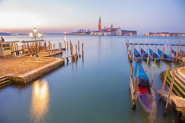 Venice - Boats and gondolas and San Giorgio Maggiore church in background in morning dusk.
