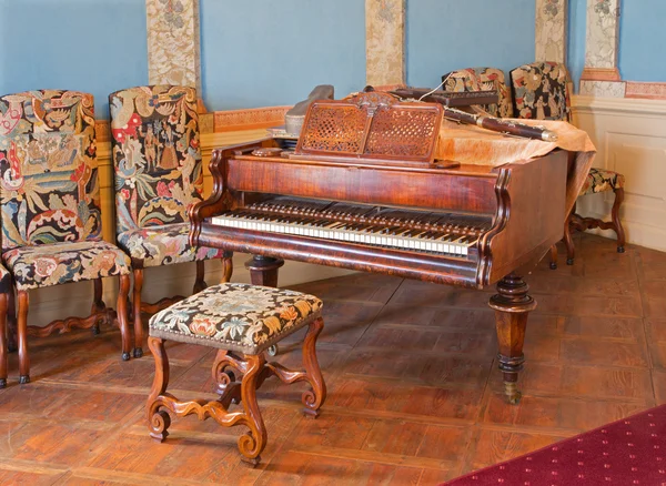 SAINT ANTON, SLOVAKIA - FEBRUARY 26, 2014: Piano in music saloon in palace Saint Anton with the handmade needlework on the chairs from 19. cent.