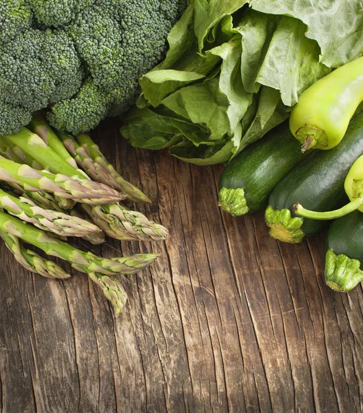 Fresh green vegetables on a wooden background.