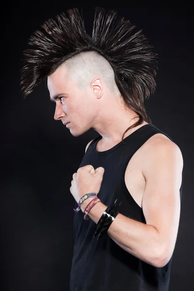 Punk man with mohawk haircut. Black shirt. Expressive face. Isolated on black background. Studio shot.
