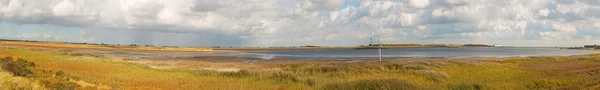 Panoramic shot of dutch landscape with sea and stormy blue cloudy sky.