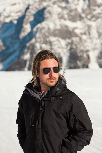 Ski man with sunglasses in rocky snow mountain landscape.