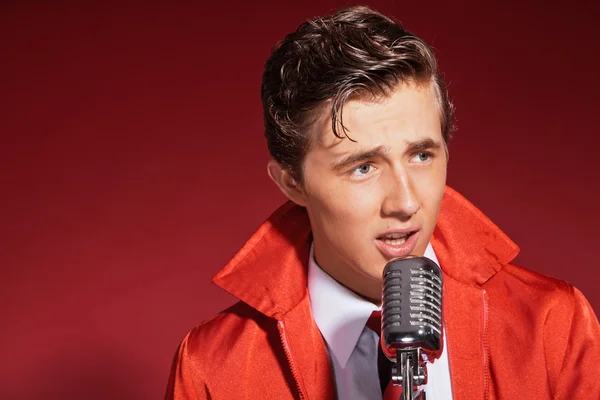 Retro fifties singer wearing red jacket with jeans and tie. Vint