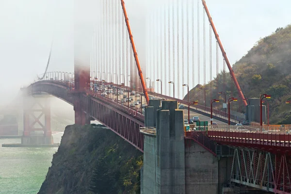 Close-up of Golden Gate Bridge with traffic. Cloudy sky. San Fra