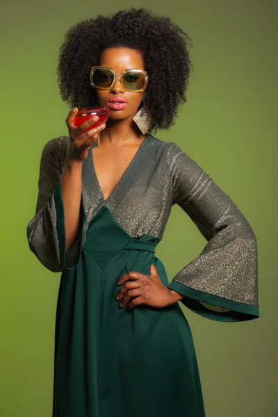 Retro 70s afro fashion woman with green dress and orange cocktai