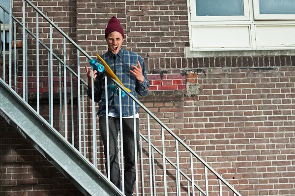 Cool skateboarder with woolen hat standing on iron stairway. His