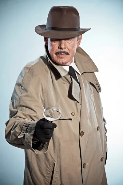 Retro detective with mustache and hat. Looking through magnifyin
