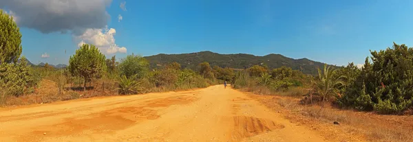 Panoramic shot of sand road in green hill landscape. Greece. Cor