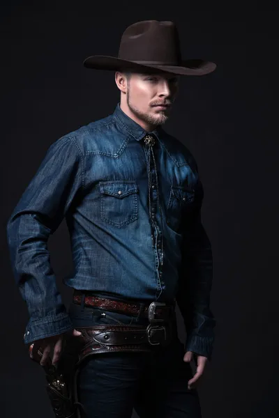 Modern fashion cowboy. Wearing brown hat and blue jeans shirt. P