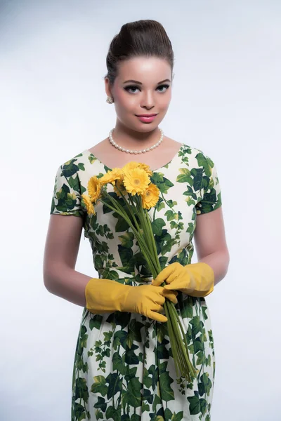 Retro 50s fashion housewife wearing yellow rubber gloves. Holdin