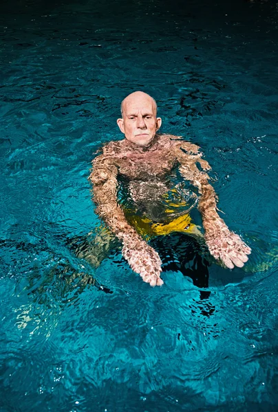 Healthy active senior man with beard in indoor swimming pool. We