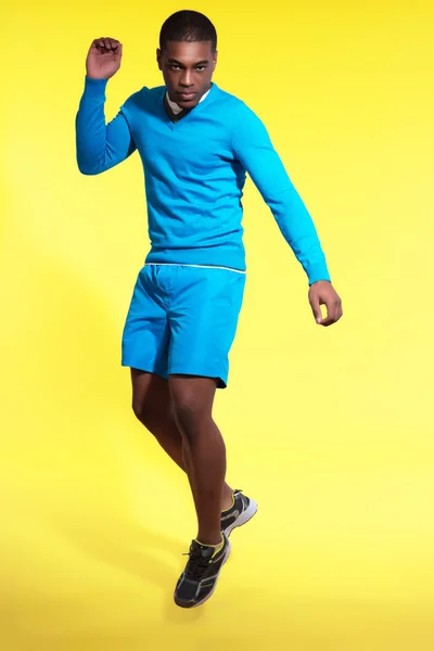 Jumping athletic black man in sportswear fashion. Wearing blue s