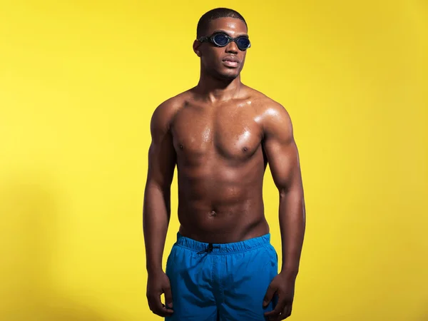 Athletic swimmer with waterdrops. Black man wearing blue swimmin