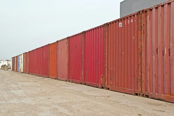 Row of red containers. Blue cloudy sky. Industrial environment.