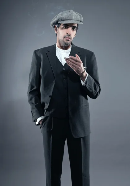 Mafia fashion man wearing grey striped suit with cap. Smoking ci