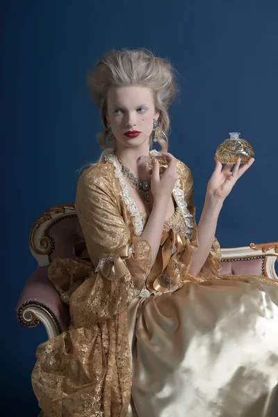 Retro baroque fashion woman wearing gold dress. Holding bottle o