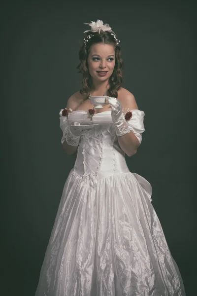 Victorian fashion woman wearing white dress. Holding porcelain t