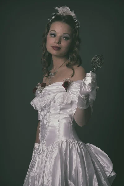 Victorian fashion woman wearing white dress. Holding silver mirr
